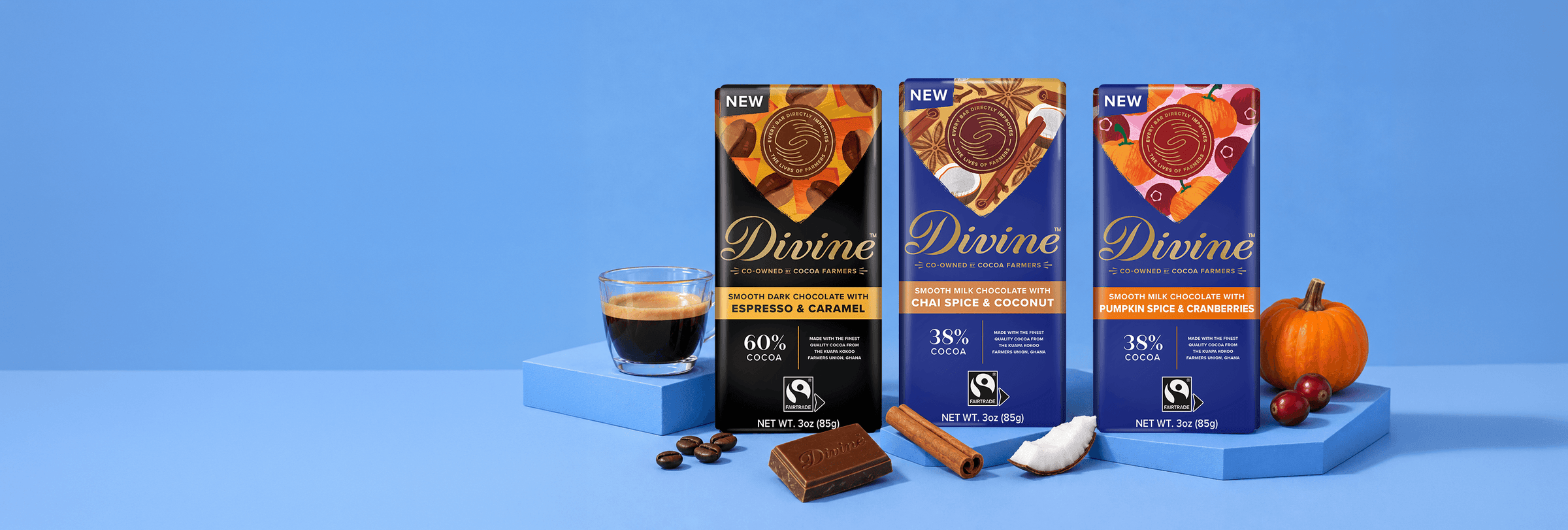 Desktop banner featuring three limited-edition Divine chocolate bars—Espresso & Caramel, Chai Spice & Coconut, and Pumpkin Spice & Cranberries—displayed with complementary ingredients including espresso, coffee beans, cinnamon sticks, coconut, pumpkin, and cranberries on a blue background.