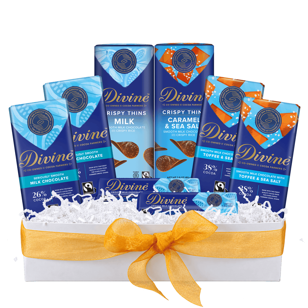 A Divine chocolate gift basket featuring six assorted Divine chocolate bars arranged in a white box filled with white shredded paper and tied with a yellow ribbon. The bars include Milk Chocolate, Caramel & Sea Salt, and Toffee & Sea Salt flavors.