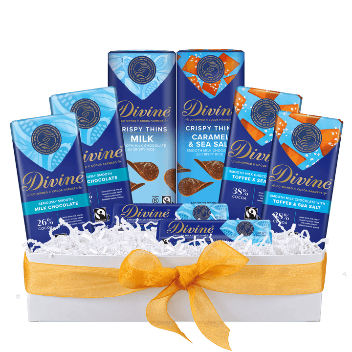 A Divine chocolate gift basket featuring six assorted Divine chocolate bars arranged in a white box filled with white shredded paper and tied with a yellow ribbon. The bars include Milk Chocolate, Caramel & Sea Salt, and Toffee & Sea Salt flavors.