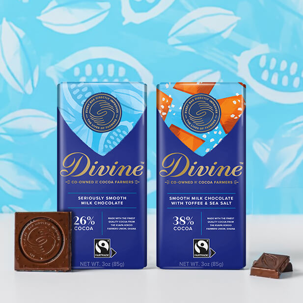 Two Divine chocolate bars against a blue floral backdrop. One is "Seriously Smooth Milk Chocolate" and the other "Smooth Milk Chocolate with Toffee & Sea Salt." There's a square chocolate piece in front, displaying the Fairtrade logo.